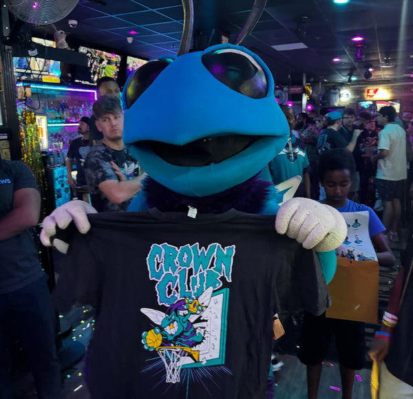 Hugo the Hornet holding up a Crown Club shirt