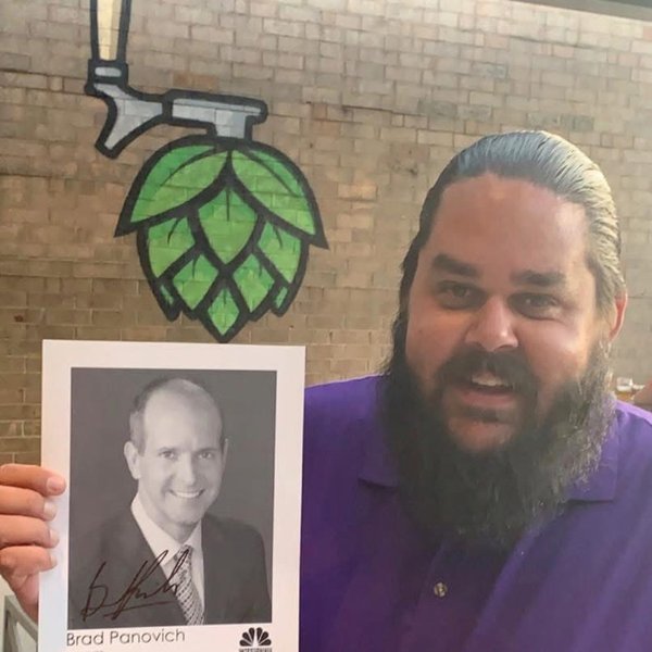 DJ Yeti in a purple shirt holding a signed photo